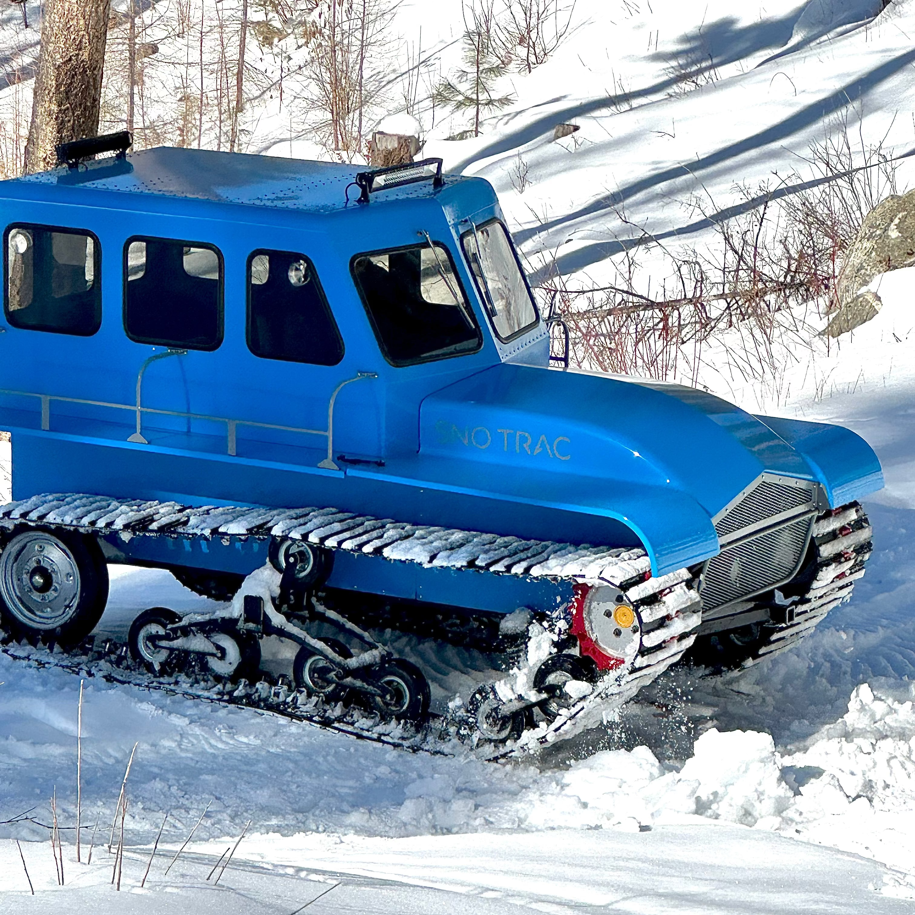 Blue Tracked Snow Vehicle in snowy terrain backcounty