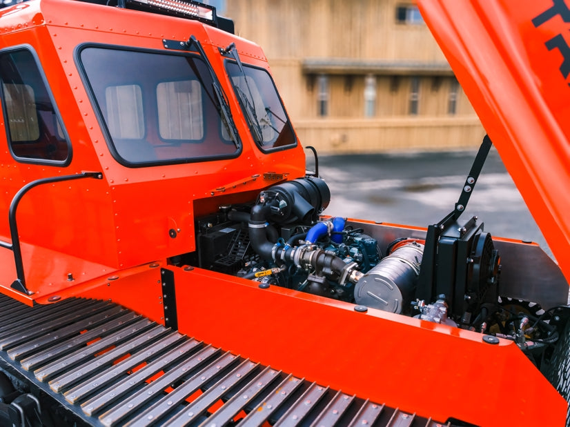 Close-up of a Sno Trac vehicle with open hood, showing engine components.