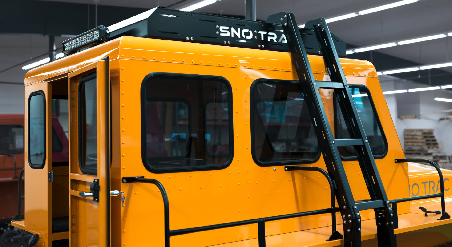 Yellow Sno Trac Vehicle with a black roof ladder utility accessory